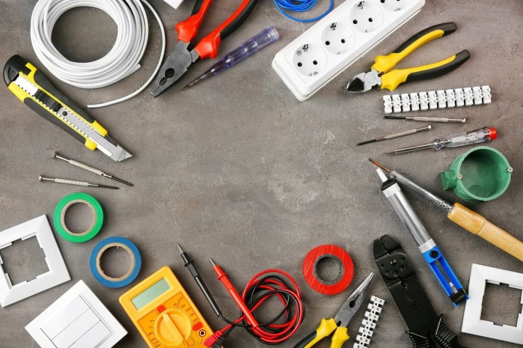 A variety of electrical tools, including pliers, screwdrivers, and wire strippers, neatly arranged on a wooden table.